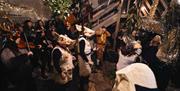 A night of folklore; people gathered around dressed in costumes in a small room