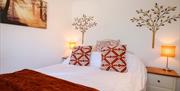 bedroom with double bed, two bedside tables and lamps, with artwork on wall