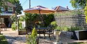 patio area with chairs, table and parasol with house in background