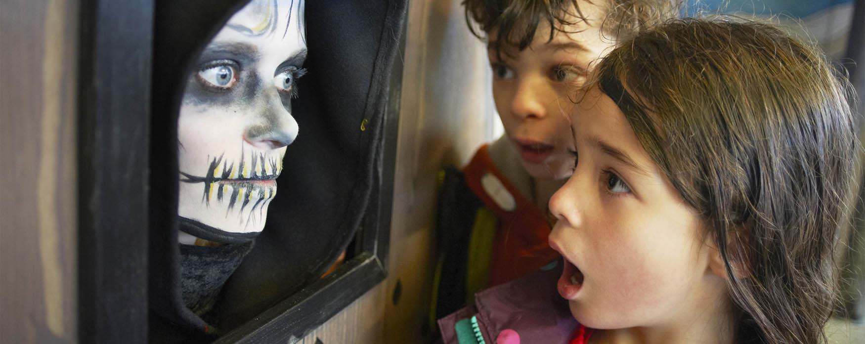 Two children looking at a halloween character