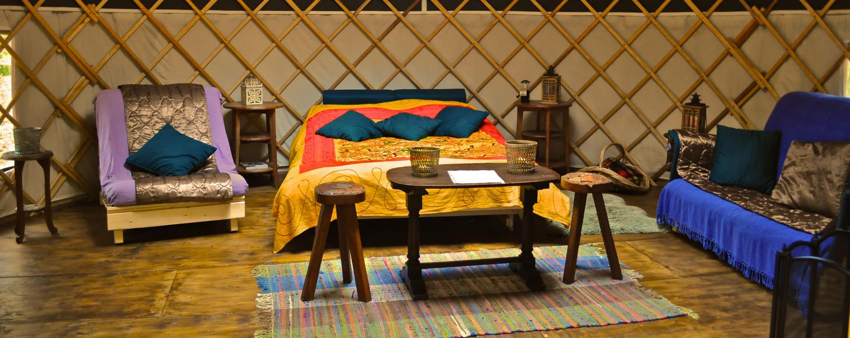 inside of yurt with plush blue sofa and gold accessories