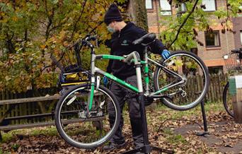 man with face mask and green bike on bike stand