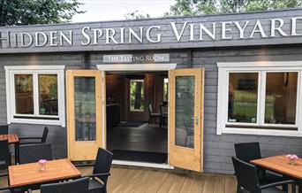 image of the vineyard tasting room - a wooden building with seating outside and inside
