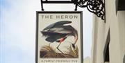 A sign outside and up high with The Heron's name and logo on it.