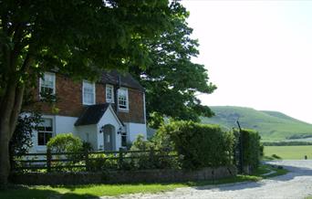 The white farmhouse with glorious green hills behind