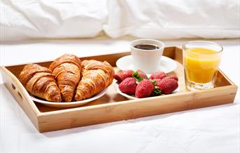 Breakfast tray of croissants and strawberries and drinks