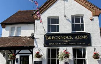 An image of the Brecknock Arms. It is painted white with a black sign in the centre of the building.