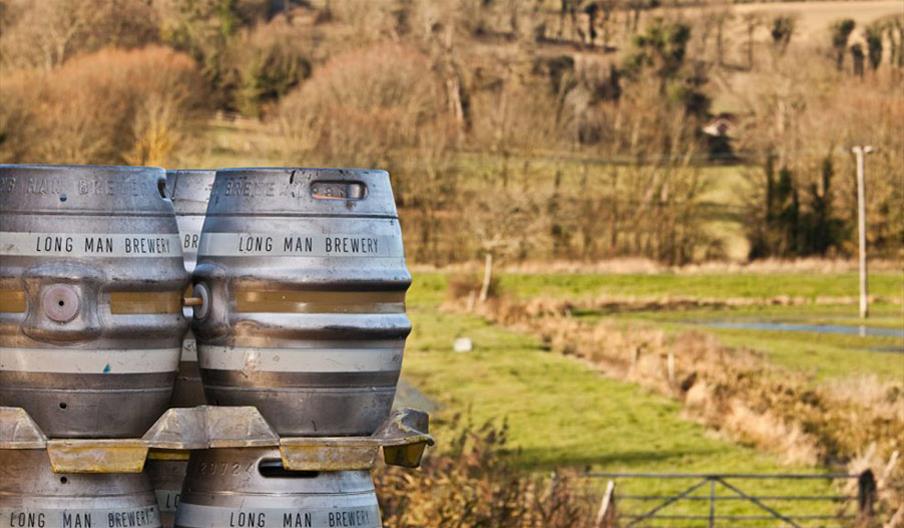casks with long man brewery written on them with green fields in background