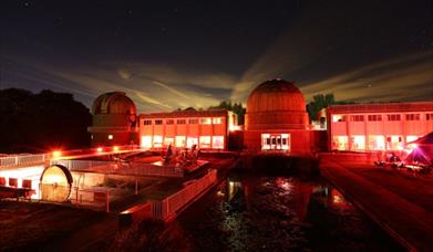Picture of telescopes at observatory science centre in dark lit lighting with red mood lighting