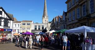 People looking around market with church spire in background