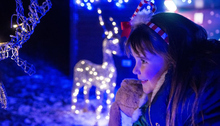 Young girl grinning surrounded by Christmas lights
