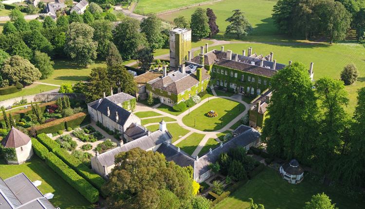 Aerial photo of a large estate with surrounding gardens, fields and trees.