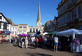 People looking around market with church spire in background