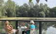 two ladies sitting and having a cup of tea near a lake