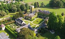 Aerial photo of a large estate with surrounding gardens, fields and trees. 