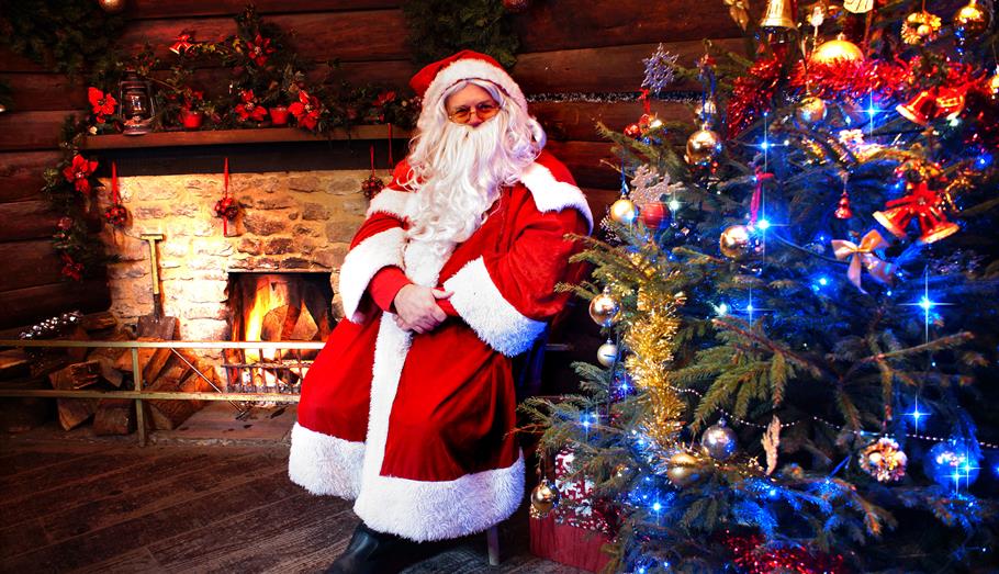 Santa standing next to a Christmas tree
