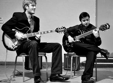 Black and white photo of duo playing guitars