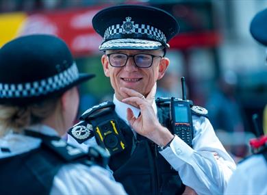 Commissioner Sir Mark Rowley in uniform on the street talking to colleagues