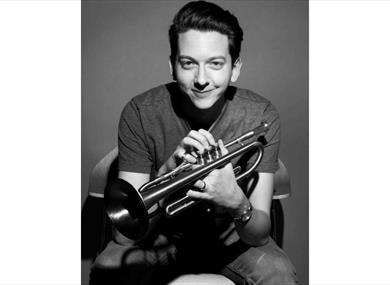 Freddie Gavita, black and white photo holding a trumpet