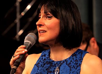 Georgia Mancio singing in a blue dress © Tatiana Gorilovksy