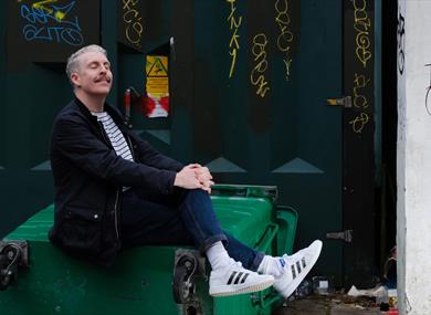 Carl Donnelly - sat posed on a tipped over bin