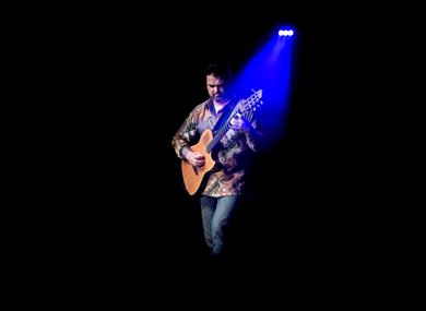 Nicolas Meier playing guitar under a blue spotlight ©Eric Humair