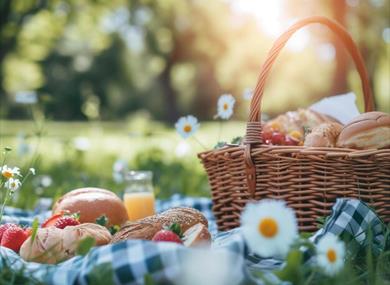 Picnic basket with bread and strawberries in a meadow with daisies