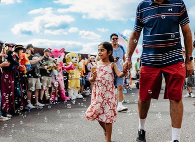 TOTfest | girl carrying ice cream and walking hand in hand through bubbles