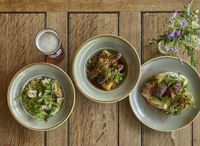 Three dishes of food and a pint of beer