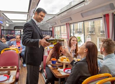 Person pouring a glass of prosecco for a passenger on Golden Tours Royal Windsor Afternoon Tea Bus Tour