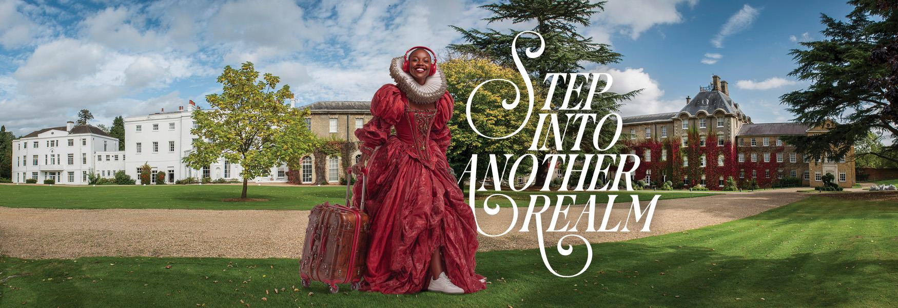 Person in historic dress pulling a suitcase and wearing headphones standing in front of De Vere Beaumont Estate
