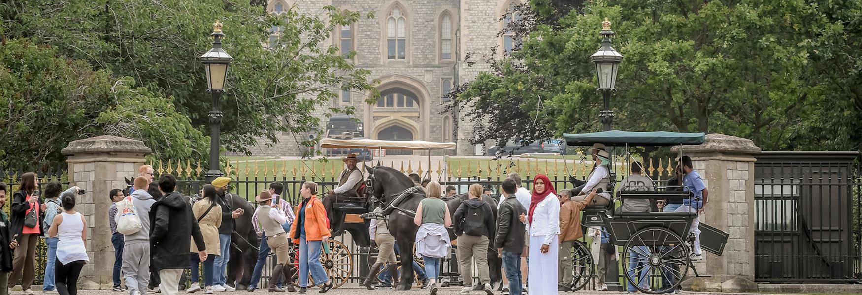 Groups of people and horse-drawn carriage on the Long Walk outside Windsor Castle