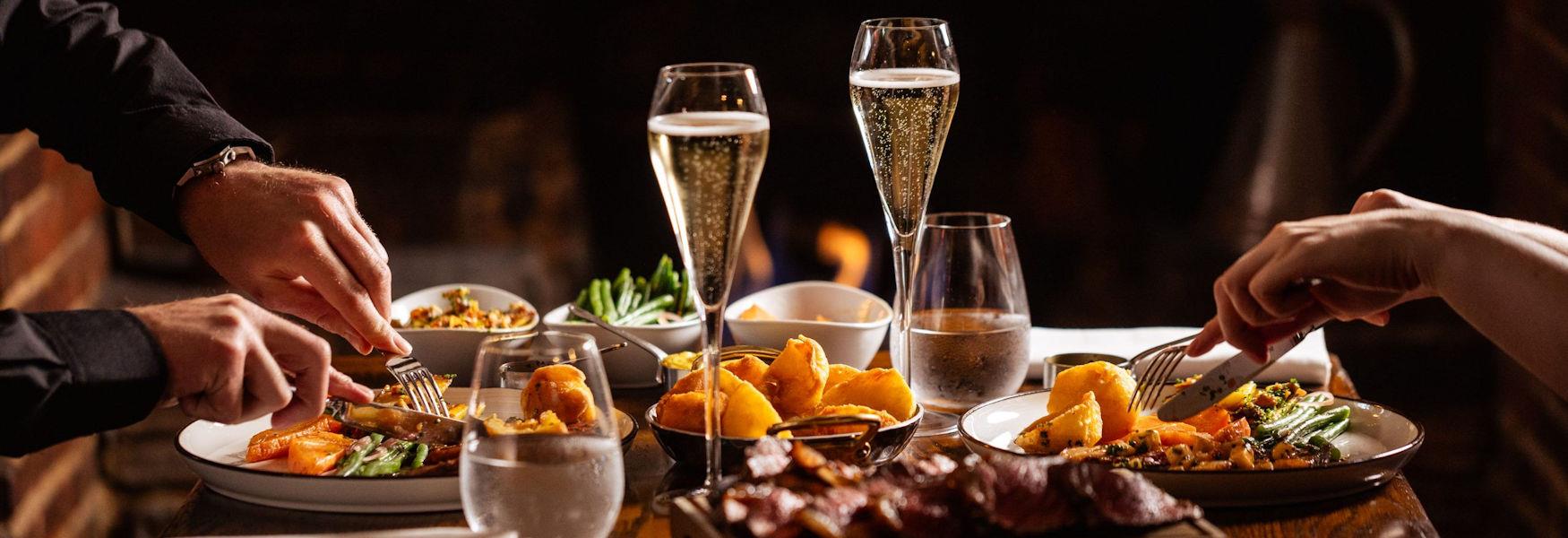 Two people eating food and drinking fizz at The Hind's Head, Bray