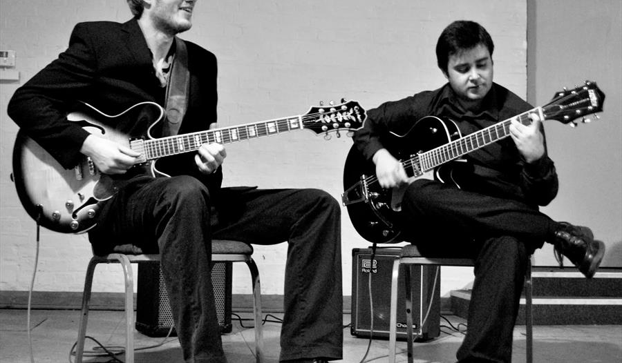 Black and white photo of duo playing guitars