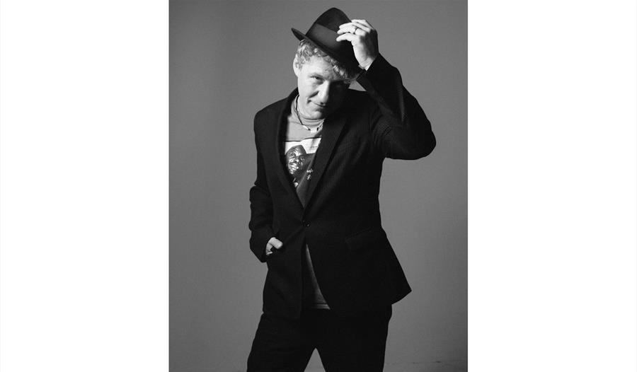 Dom Pipkin, black and white, raising his hat