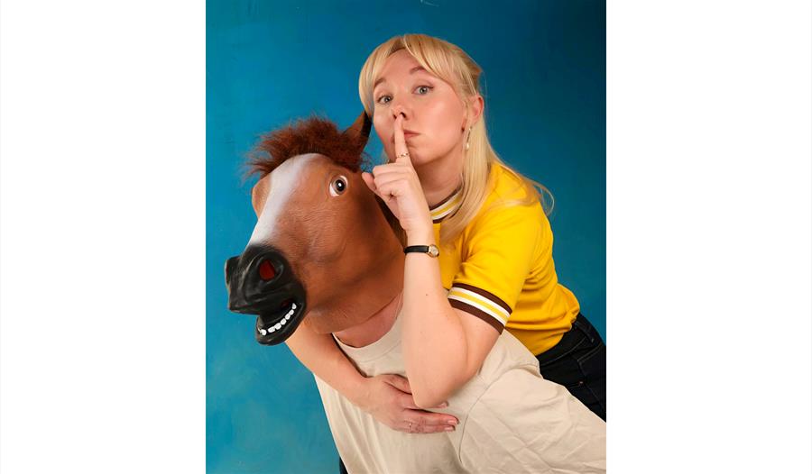 Becky Umbers - piggybacking a man in a rubber horse head mask