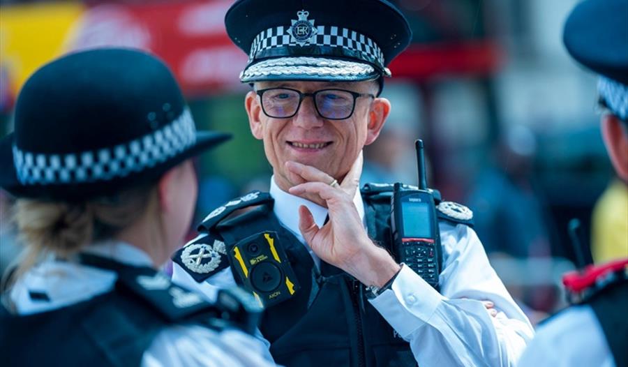 Commissioner Sir Mark Rowley in uniform on the street talking to colleagues