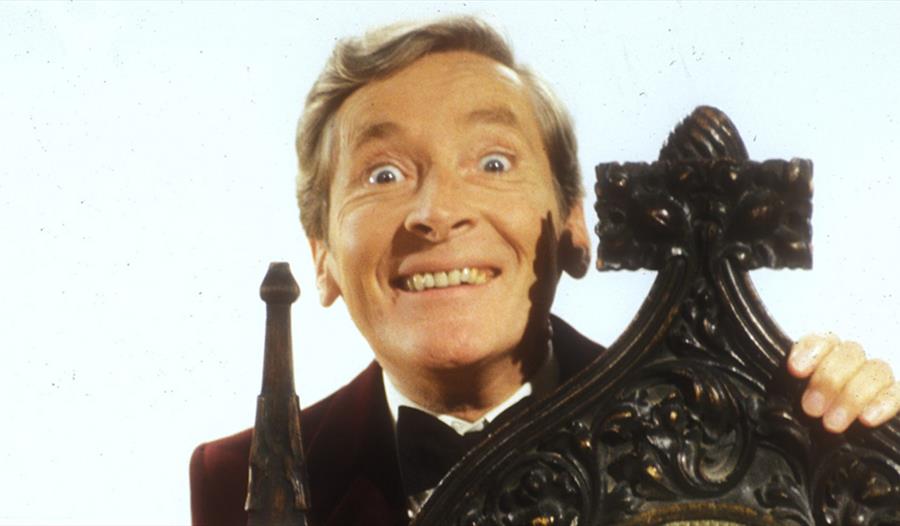 Kenneth Williams behind a wooden chair