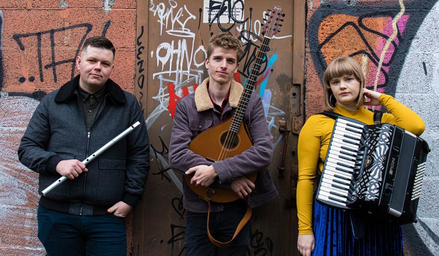Jon Doran and The Northern Assembly - group holding traditional folk instruments in front of graffitied wall