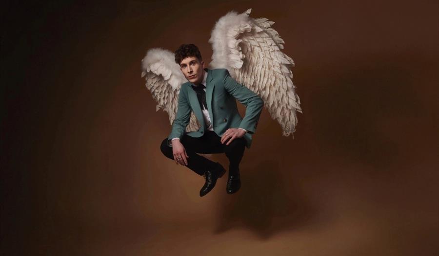 Larry Dean - suited, floating with angel wings