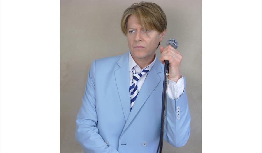 Paul Bowie promo, blue suit leaning against a mic stand