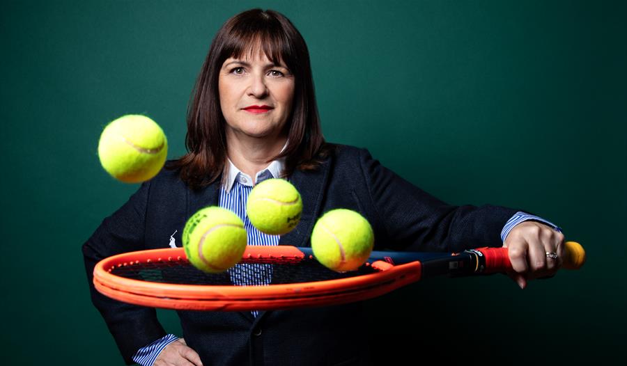 Pauline Eyre suited holding a tennis racket catching tennis balls