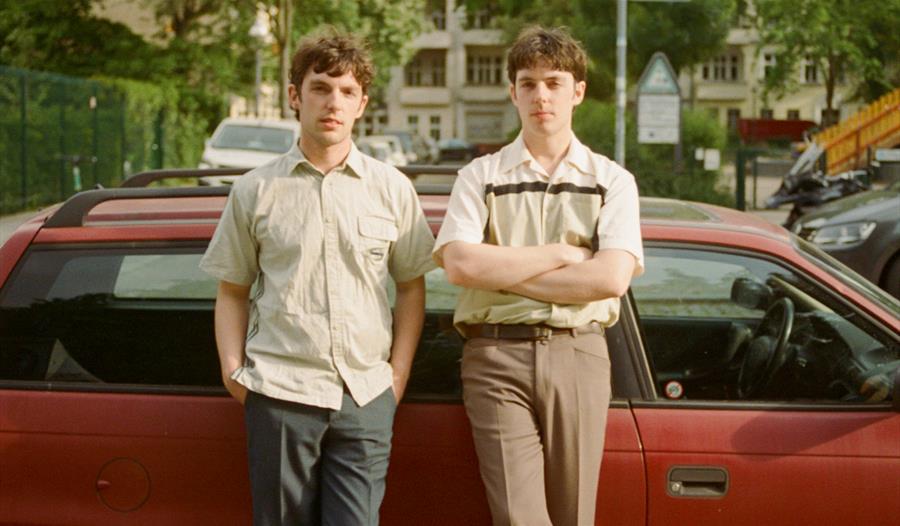 The Ocelots - two men stood against a car