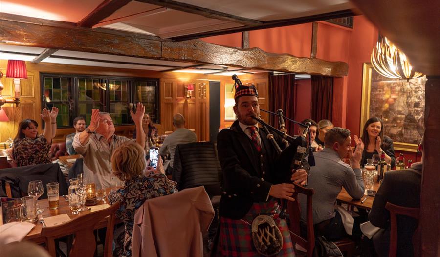 Burns Night supper at The Hind's Head, Bray, with piper in the foreground