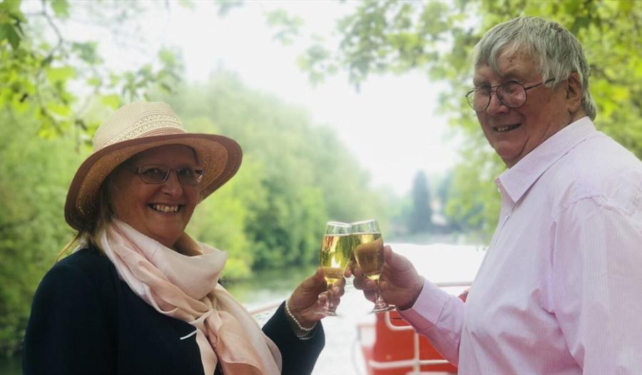 Two people clinking wine glasses on board The Georgian | Windsor & Maidenhead Boat Company