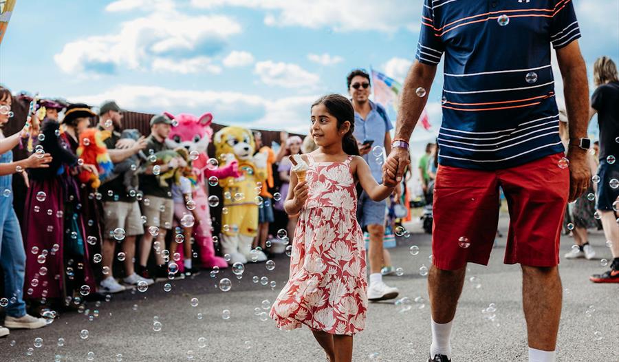 TOTfest | girl carrying ice cream and walking hand in hand through bubbles