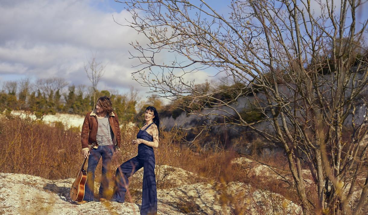 Hannah Sanders & Ben Savage 2025 - posed in nature with a guitar