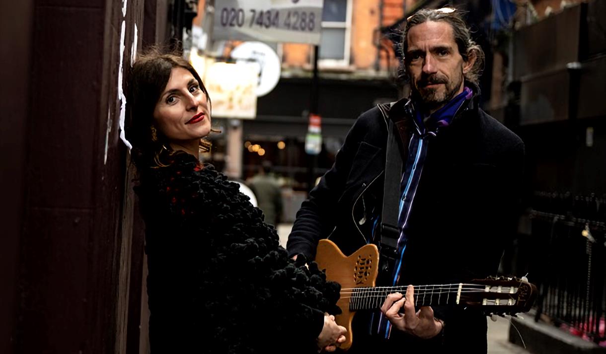 Irene & Luca, man holding a guitar alongside a woman on a London street