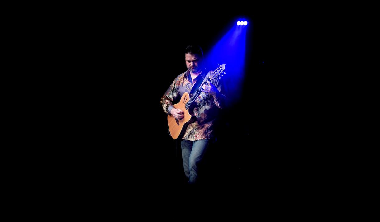 Nicolas Meier playing guitar under a blue spotlight ©Eric Humair