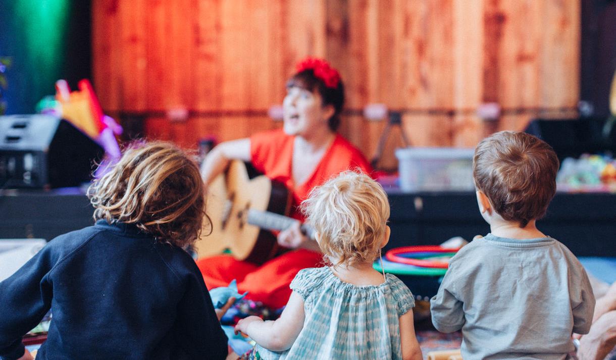 Person playing guitar as children watch